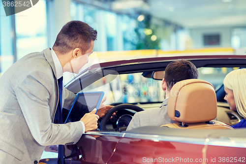 Image of happy couple with car dealer in auto show or salon