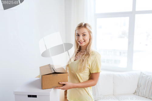 Image of smiling young woman with cardboard box at home