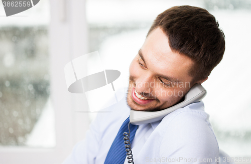 Image of happy businessman calling on phone at office