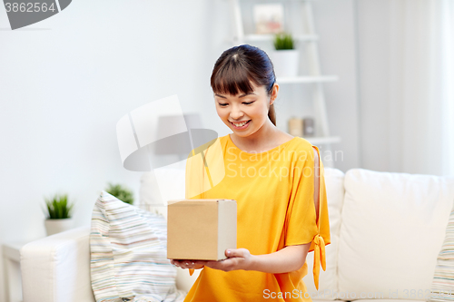 Image of happy asian young woman with parcel box at home