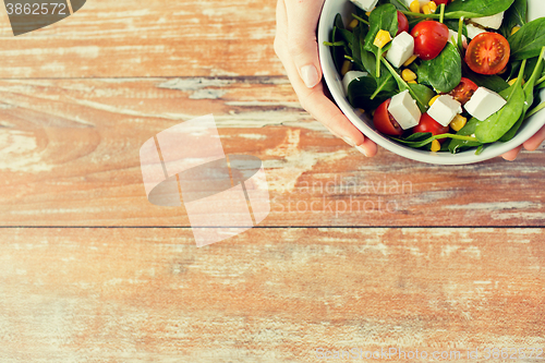 Image of close up of young woman hands with salad bowl
