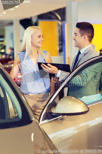 Image of happy woman with car dealer in auto show or salon