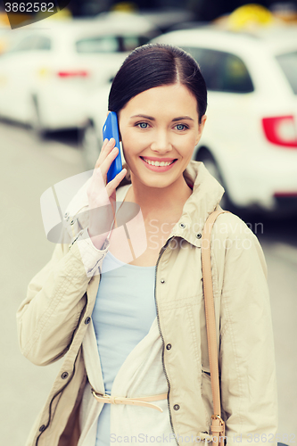 Image of smiling woman with smartphone over taxi in city