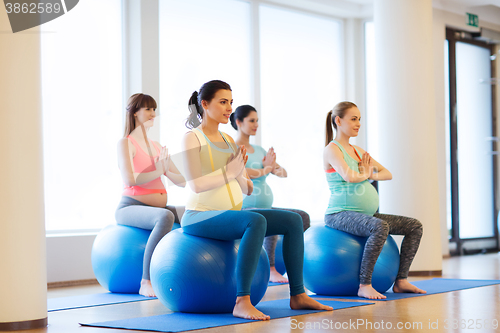 Image of happy pregnant women exercising on fitball in gym