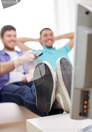 Image of close up of happy male friends watching tv at home