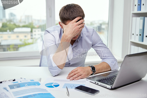 Image of stressed businessman with papers in office