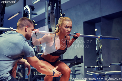 Image of man and woman with bar flexing muscles in gym