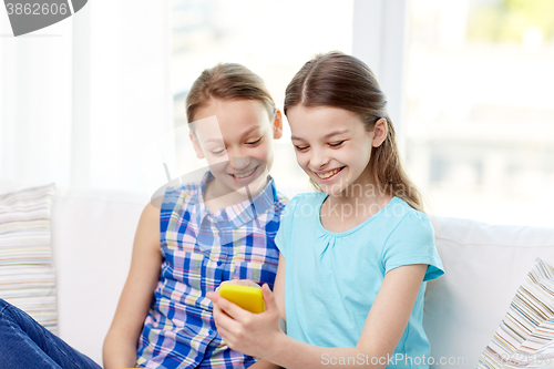 Image of happy girls with smartphone sitting on sofa