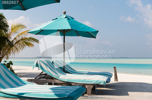 Image of parasol and sunbeds by sea on maldives beach