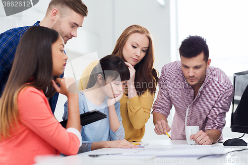 Image of creative team with blueprint working at office