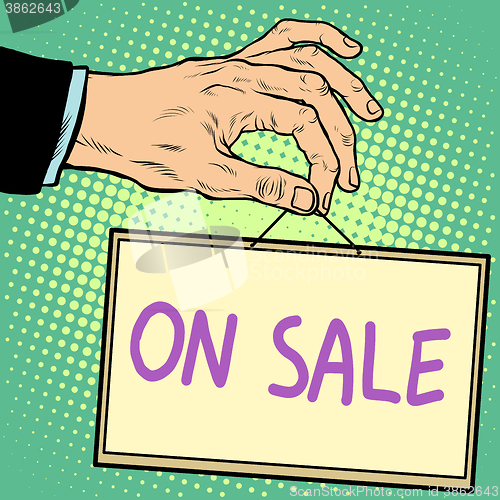 Image of Hand holding a sign on sale