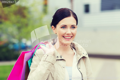 Image of smiling woman with shopping bags coming from sale