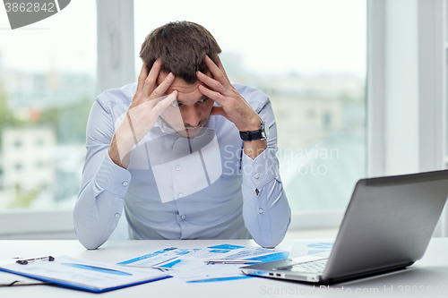 Image of stressed businessman with laptop at office