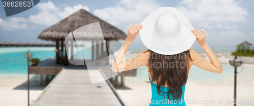 Image of woman in swimsuit and sun hat from back on beach