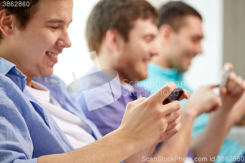 Image of close up of happy friends with smartphones at home