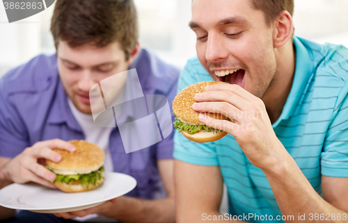 Image of close up of friends eating hamburgers at home
