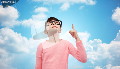 Image of happy little girl in eyeglasses pointing finger up