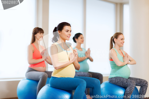 Image of happy pregnant women exercising on fitball in gym