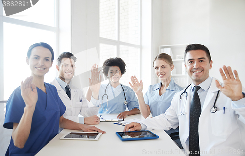 Image of happy doctors meeting and waving hands at hospital