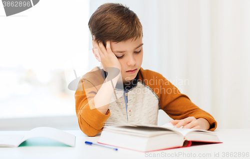 Image of student boy reading book or textbook at home