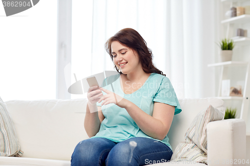 Image of happy plus size woman with smartphone at home
