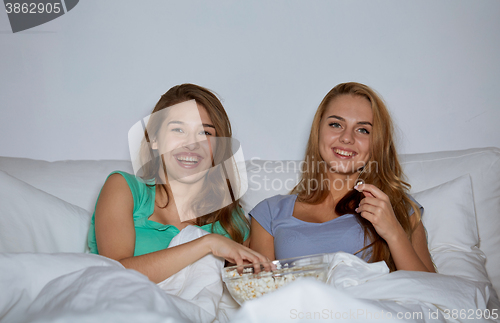 Image of happy friends with popcorn and watching tv at home