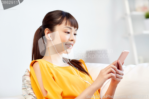 Image of happy asian woman with smartphone and earphones