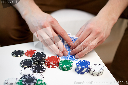 Image of close up of male hand with playing cards and chips