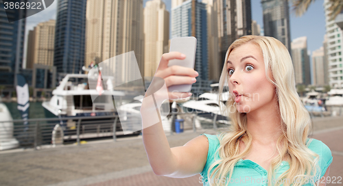 Image of funny young woman taking selfie with smartphone