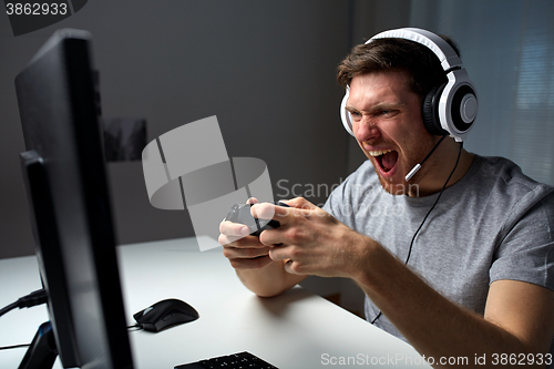 Image of man in headset playing computer video game at home