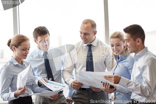 Image of happy business people with papers talkig in office