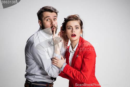 Image of Young man telling gossips to his woman colleague at the office