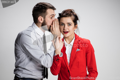 Image of Young man telling gossips to his woman colleague at the office