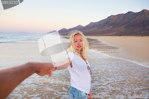 Image of Romantic couple holding hands on beach.