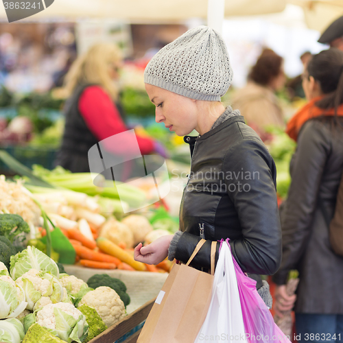 Image of Woman buying vegetable at local food market. 