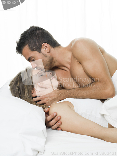 Image of man kissing his partner sweetly in white bed