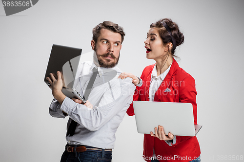 Image of The young businessman and businesswoman with laptops  communicating on gray background