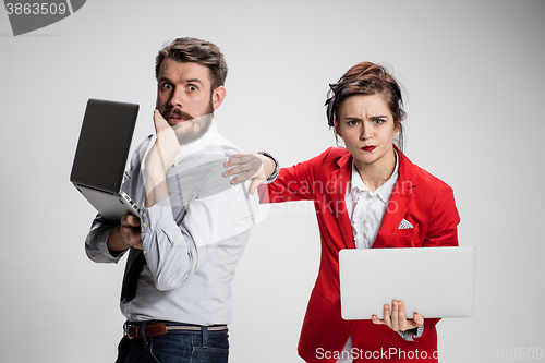 Image of The young businessman and businesswoman with laptops  communicating on gray background