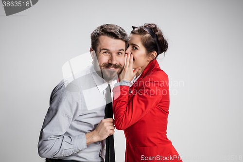 Image of Young man telling gossips to his woman colleague at the office