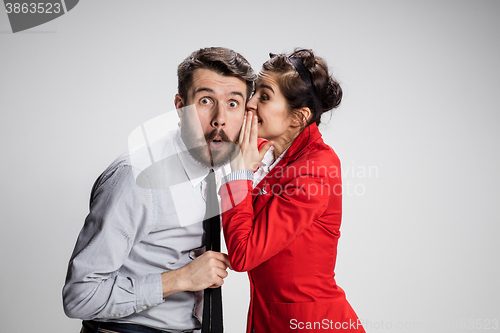 Image of Young man telling gossips to his woman colleague at the office