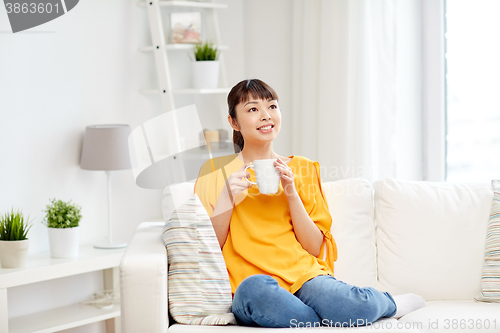 Image of happy asian woman drinking from tea cup