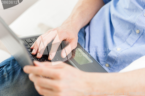 Image of close up of man typing on laptop computer at home