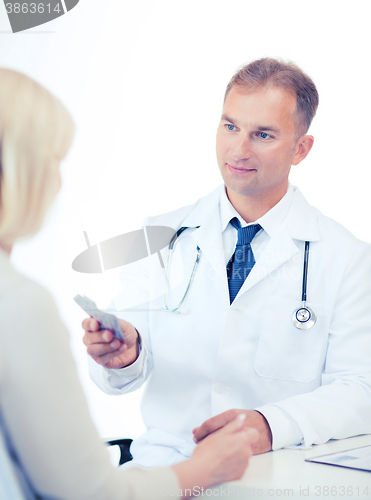 Image of doctor giving tablets to patient in hospital