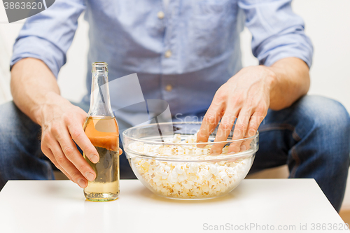 Image of close up of man with popcorn and beer at home