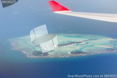 Image of close up of airplane wing above island in ocean