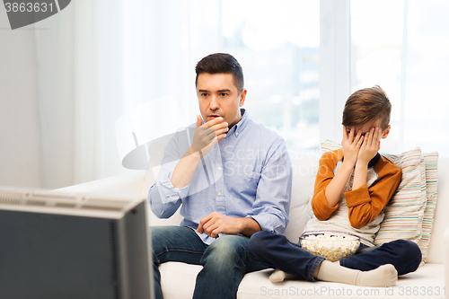Image of father and son watching horror movie on tv at home