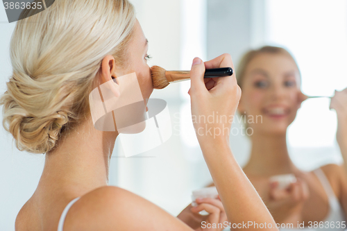 Image of woman with makeup brush and powder at bathroom