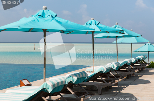 Image of parasol and sunbeds by sea on maldives beach