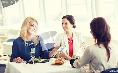 Image of happy women giving birthday present at restaurant