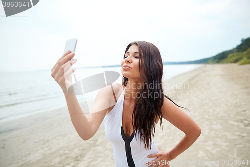 Image of young woman taking selfie with smartphone